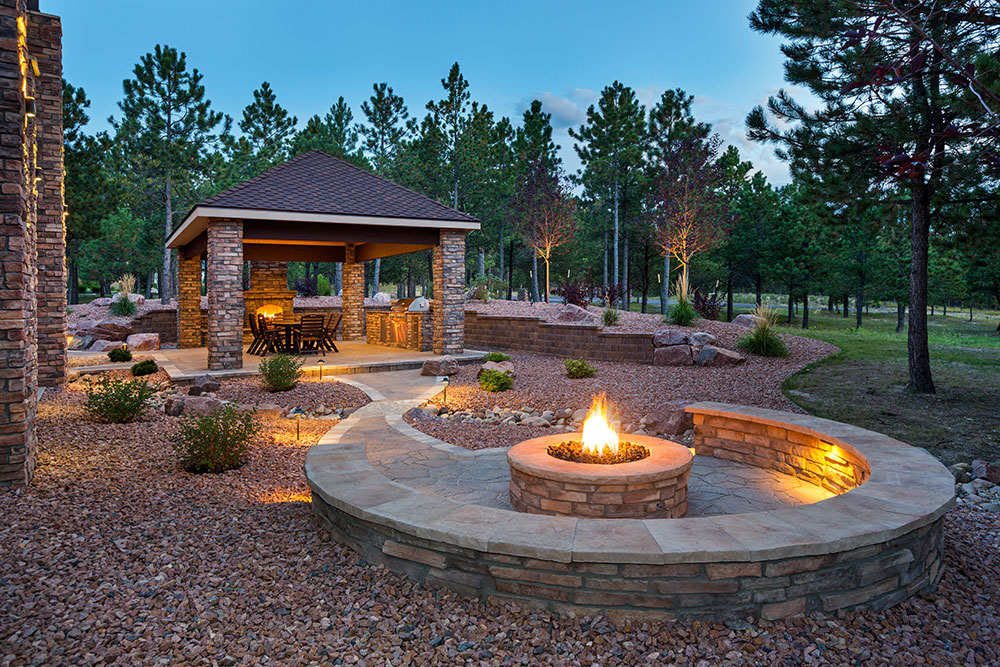 Lavish backyard featuring a firepit, covered dining area and pristine landscaping